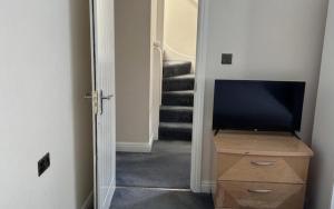 a hallway with a television on a dresser and a staircase at Double Room Private Bathroom Parking South Croydon in Addington +9 photos