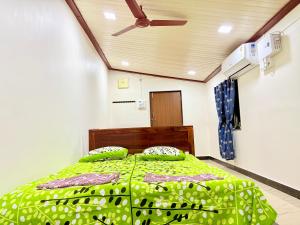 a bedroom with a bed with a green comforter and pillows at Shree Kelbai Homestay in Malvan