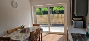 a dining room with a table and a kitchen with a sliding glass door at Tullywolly Cottage, Irvinestown in Stralongford