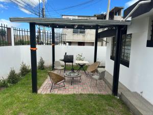a patio with chairs and a table with a laptop on it at Flor de Naranjo in Tabacundo