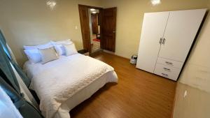 a bedroom with a bed with white sheets and pillows at Flor de Naranjo in Tabacundo