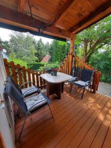 a wooden deck with a table and chairs on it at Rika Vendégház in Pécsvárad