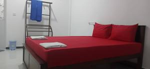 a bed with red sheets and red pillows and a ladder at Sivas friendly guest house in Nilaveli +1 photo
