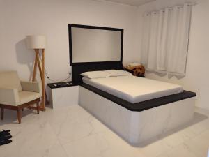 a bed in a room with a chair and a bedvisor at Motel Hotel Le Premier in Venâncio Aires