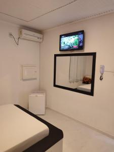 a room with a bed and a tv on the wall at Motel Hotel Le Premier in Venâncio Aires