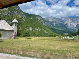 a field with a church and mountains in the background at Lokthi Guesthaose in Theth
