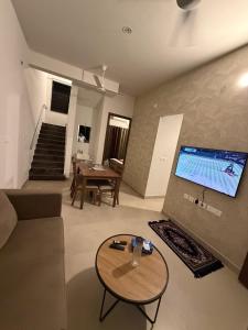 a living room with a large tv and a table at coastal coral in Tirupporūr