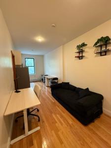 a living room with a black couch and a desk at Chic Times Square 1BR Entire Apt - Private Kitchen & Bath - Hosts 4 in New York
