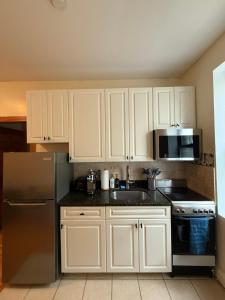 a kitchen with white cabinets and a stainless steel refrigerator at Chic Times Square 1BR Entire Apt - Private Kitchen & Bath - Hosts 4 in New York
