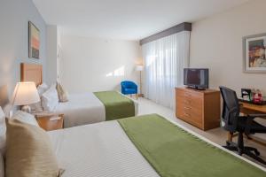 um quarto de hotel com duas camas e uma secretária e uma televisão em Wyndham Garden Playa del Carmen em Playa del Carmen