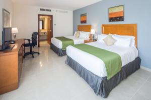 a hotel room with two beds and a television at Wyndham Garden Playa del Carmen in Playa del Carmen