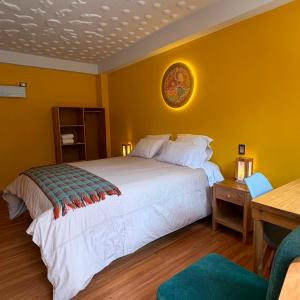 a bedroom with a white bed and a yellow wall at Pisac Inca Guest House in Pisac