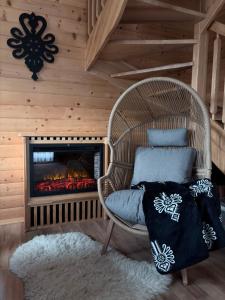 a wicker chair in a room with a fireplace at Domek na Hubce 2 Blisko jeziora Velo Czorsztyn in Maniowy