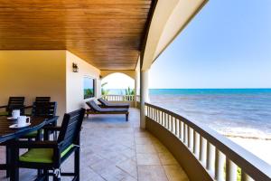 a balcony with a table and chairs on the beach at Beachfront 2BR Villa with Pool & Spacious Layout in Placencia