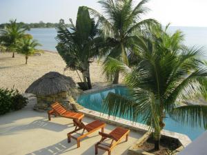 a resort with a pool and two chairs and palm trees at Beachfront 2BR Villa with Pool & Spacious Layout in Placencia