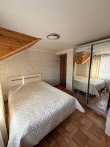 a bedroom with a white bed and a mirror at Колиска Карпат in Slavske