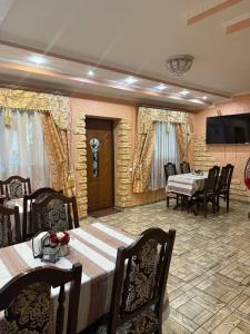a dining room with tables and chairs and a television at Колиска Карпат in Slavske