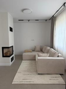 a white living room with a couch and a tv at Apartmány Vysoké in Vysoké nad Jizerou