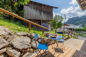 a patio with a table and chairs and a stone wall at Les Évouettes Châtel village in Châtel