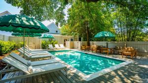 a swimming pool with chairs and umbrellas in a backyard at The Iris in Charleston