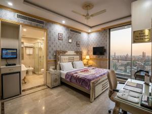 a bedroom with a bed and a television and a bathroom at Hotel The Shalimar in Lahore
