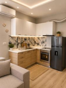 a kitchen with a stainless steel refrigerator and a couch at Cozy Apartment Astiri in Tirana