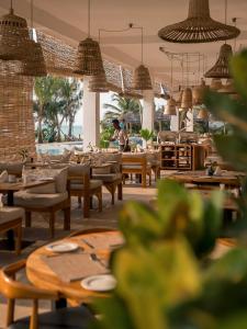 a restaurant with tables and chairs and people in the background at Kaskazi Hotel Zanzibar in Jambiani