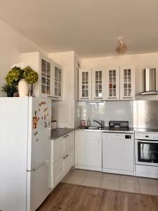 a kitchen with white cabinets and a white refrigerator at 3 pièces proche Disney in Serris
