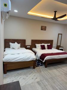a bedroom with two beds and a ceiling fan at Hotel Omkara View Palace in Godarpura +3 photos