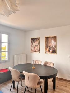 a dining room with a black table and chairs at 3 pièces proche Disney in Serris +17 photos