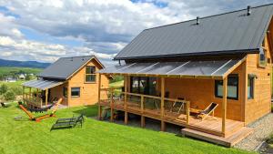 a log cabin with a deck and a house at Górska Przystań in Grywałd
