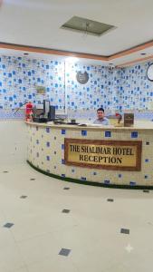 a man standing behind a counter at a shahmut hotel reception at Hotel The Shalimar in Lahore