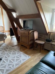 a living room with a tv on a wooden cabinet at Le balcon in Beaumont-le-Hareng