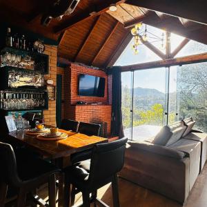 a dining room with a table and a couch at Chalé Brisa Verde in Rio dos Cedros