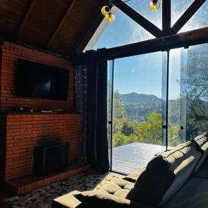 a living room with a couch and a large window at Chalé Brisa Verde in Rio dos Cedros