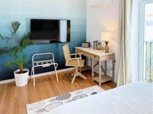 a bedroom with a desk and a tv on a blue wall at Casa Apollo Guesthouse in Faro