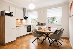 a kitchen with white cabinets and a wooden table and chairs at Kampowski Apartments Bad Nauheim in Bad Nauheim