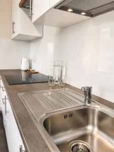 a stainless steel sink in a kitchen with white cabinets at Apartamenty ABRACADABRA in Ustroń +100 photos