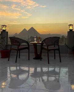 two chairs and a table on a balcony with pyramids at Pyramids Giza inn in Cairo