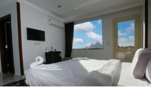 a bedroom with a white bed and a large window at Pyramids Giza inn in Cairo