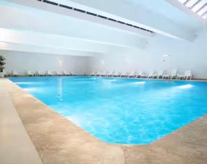a large swimming pool with blue water in a building at VILLA EVASION Aglou Center in Zaouia Sidi Ouaggag