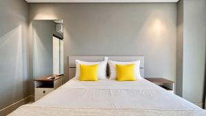 a bedroom with a large bed with yellow pillows at Flat Elegante, Confortável e Com Uma Bela Vista in Campo Grande