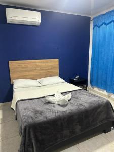 a bedroom with a bed with a blue wall at Hotel Real del Valle in Valledupar