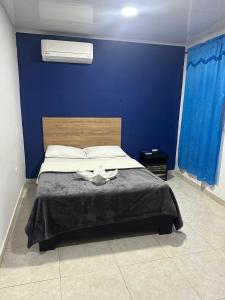 a bedroom with a bed with a blue wall at Hotel Real del Valle in Valledupar