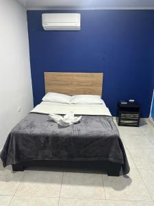 a bedroom with a bed with a blue wall at Hotel Real del Valle in Valledupar
