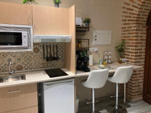 a kitchen with a sink and a counter with stools at Apartamentos turísticos Desiree in Arévalo +31 photos