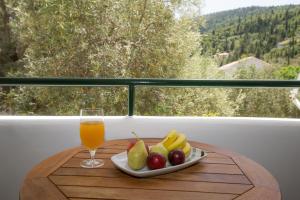 a plate of fruit on a table with a glass of orange juice at Sofia and Soul Studios in Kalamitsi