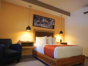 a hotel room with a bed and a chair at Hotel Buen Valle in Torreón +27 photos