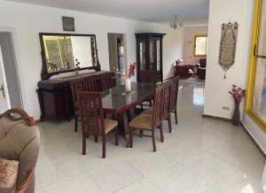 a dining room with a table and chairs and a piano at فيلا بسين خاص in Dawwār Abū Maḩrūs
