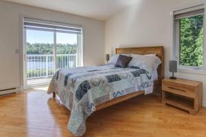 ein Schlafzimmer mit einem Bett und einem großen Fenster in der Unterkunft L'échappée du lac in Saint-Nazaire